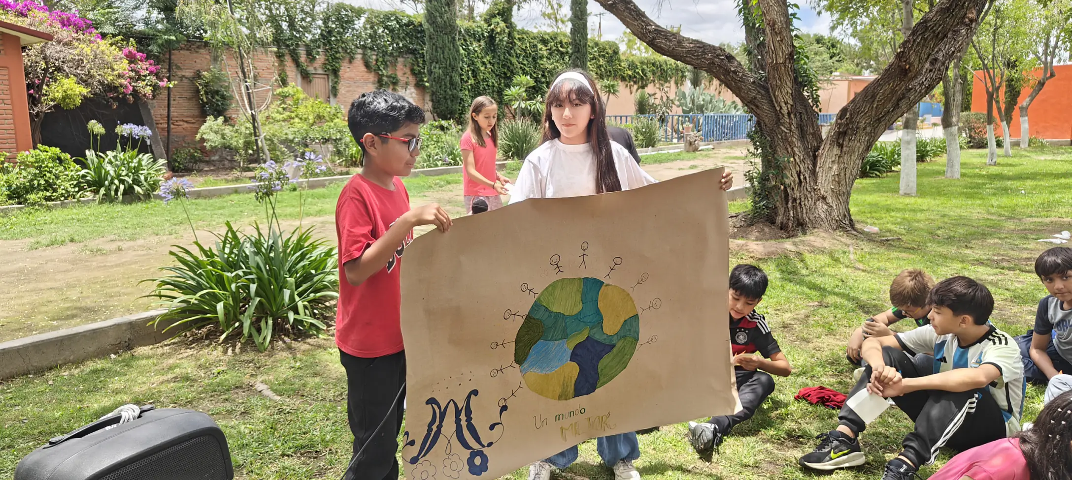 Niños mostrando un cartel del cuidado del planeta en el jardín