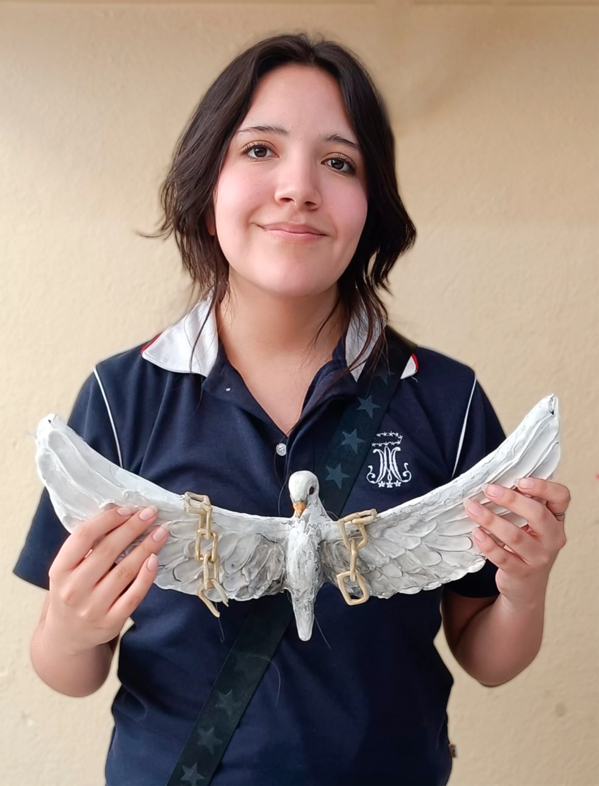 Alumna sostiene una escultura de paloma con alas abiertas