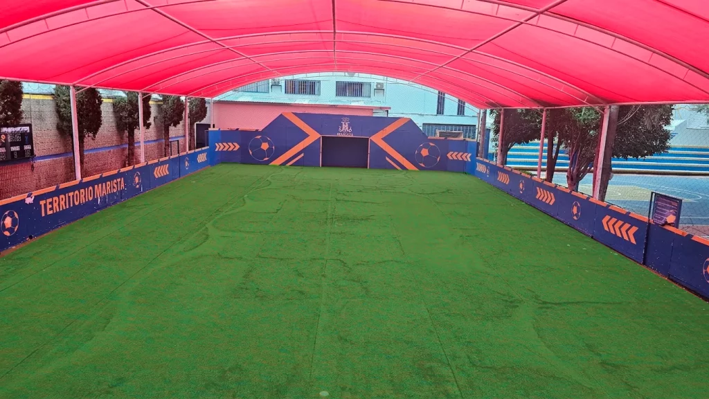 Cancha de fútbol de pasto sintético bajo una lona roja