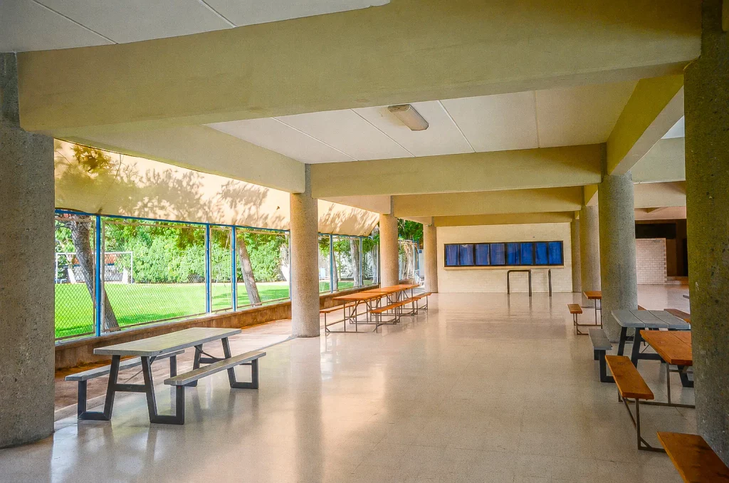 Comedor con mesas y bancas junto a los ventanales