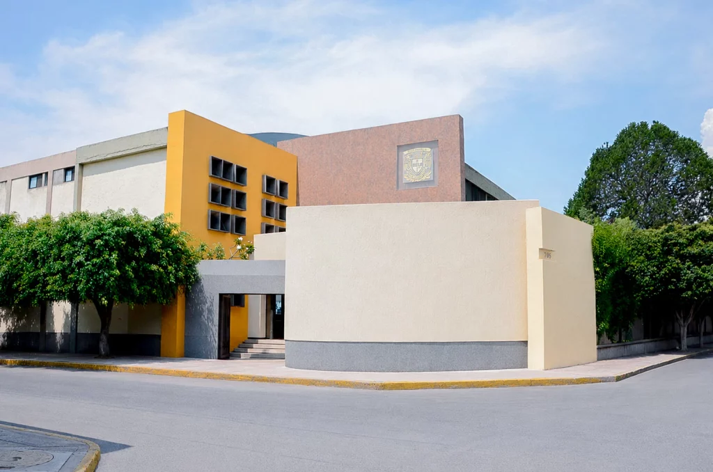 Fachada del plantel con volúmenes amarillo y blanco