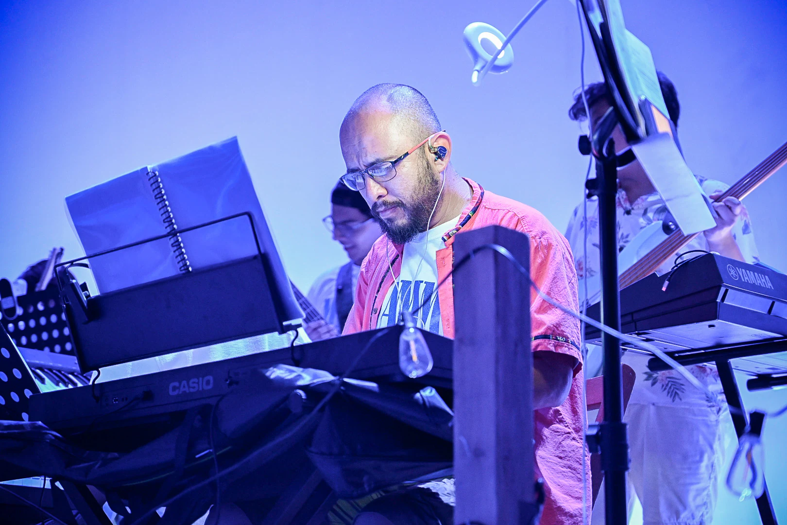 Músico en el teclado bajo luz azul durante la Revista Musical