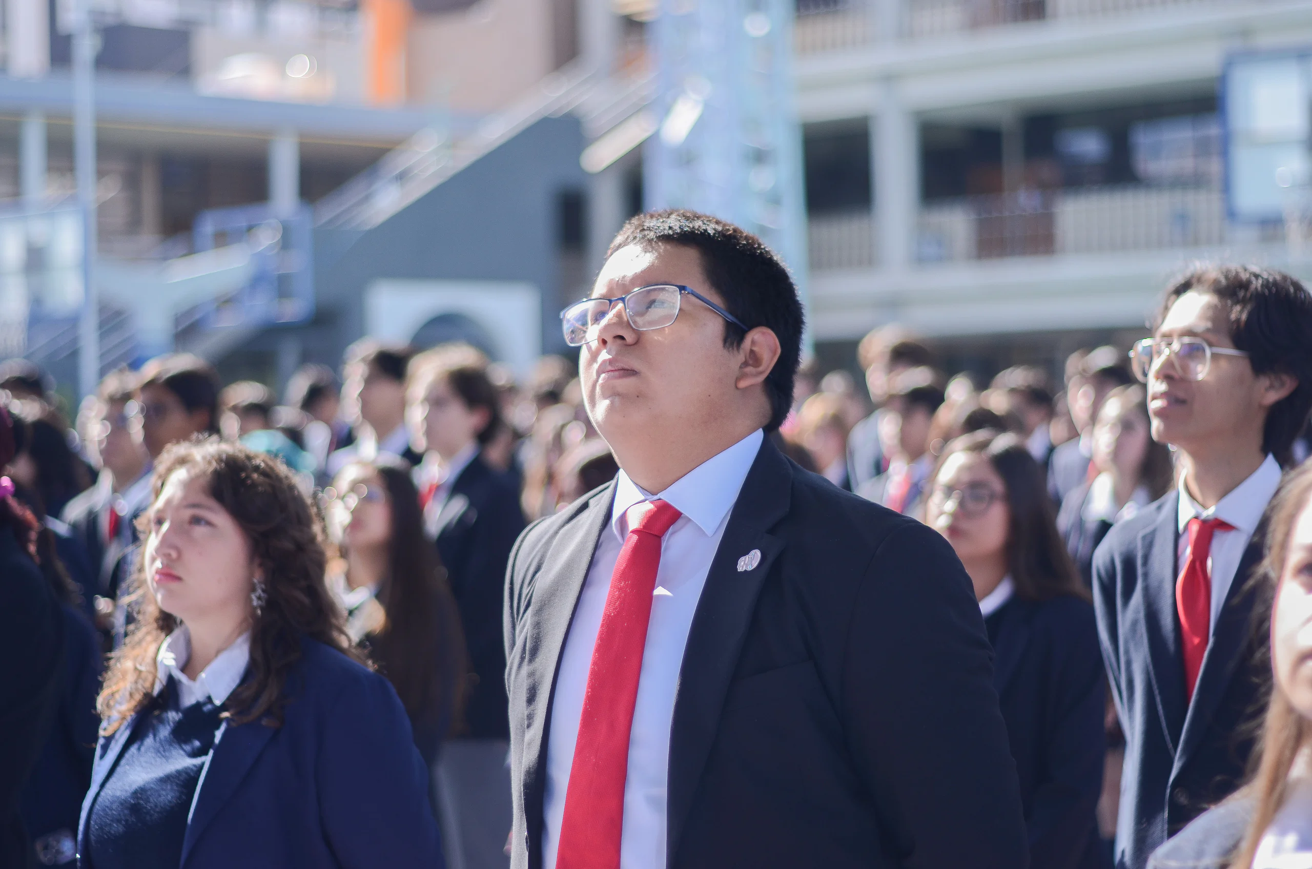 Alumnos de preparatoria con uniforme formal en un acto en el patio