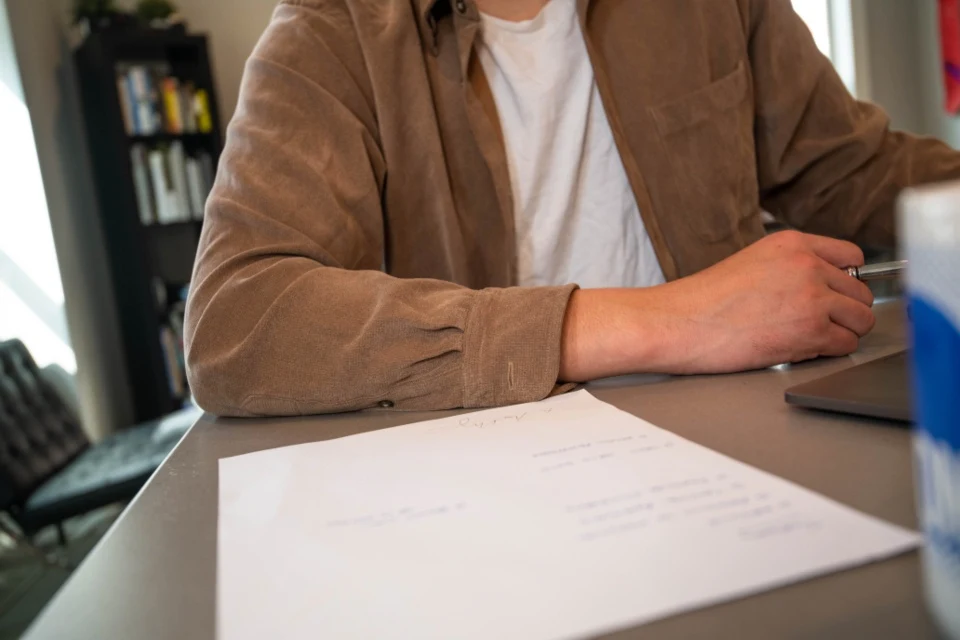 Persona escribiendo en una hoja sobre un escritorio
