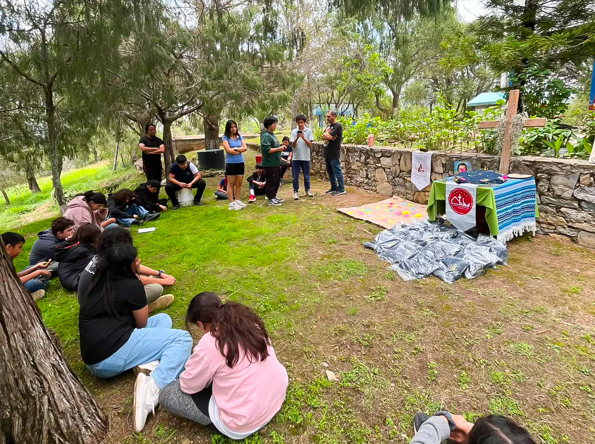 Sesión de formación al aire libre, sentados en el pasto junto a una cruz