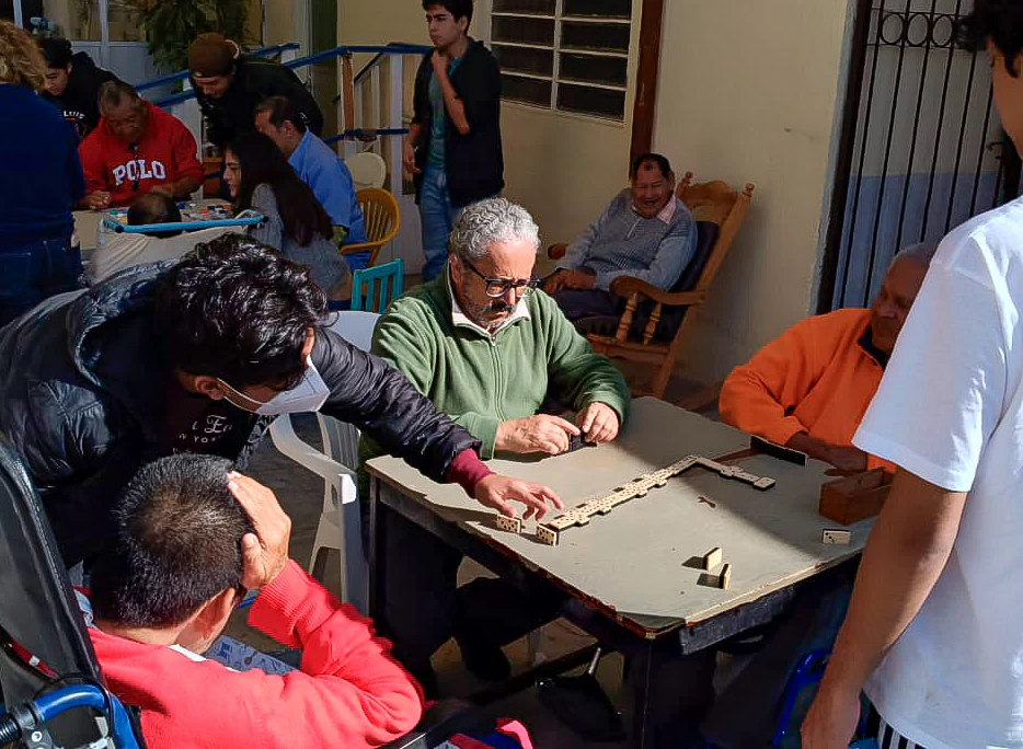 Voluntarios jugando dominó con adultos mayores