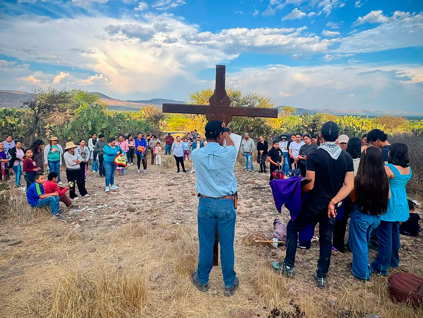 Grupo en oración frente a una cruz en el cerro