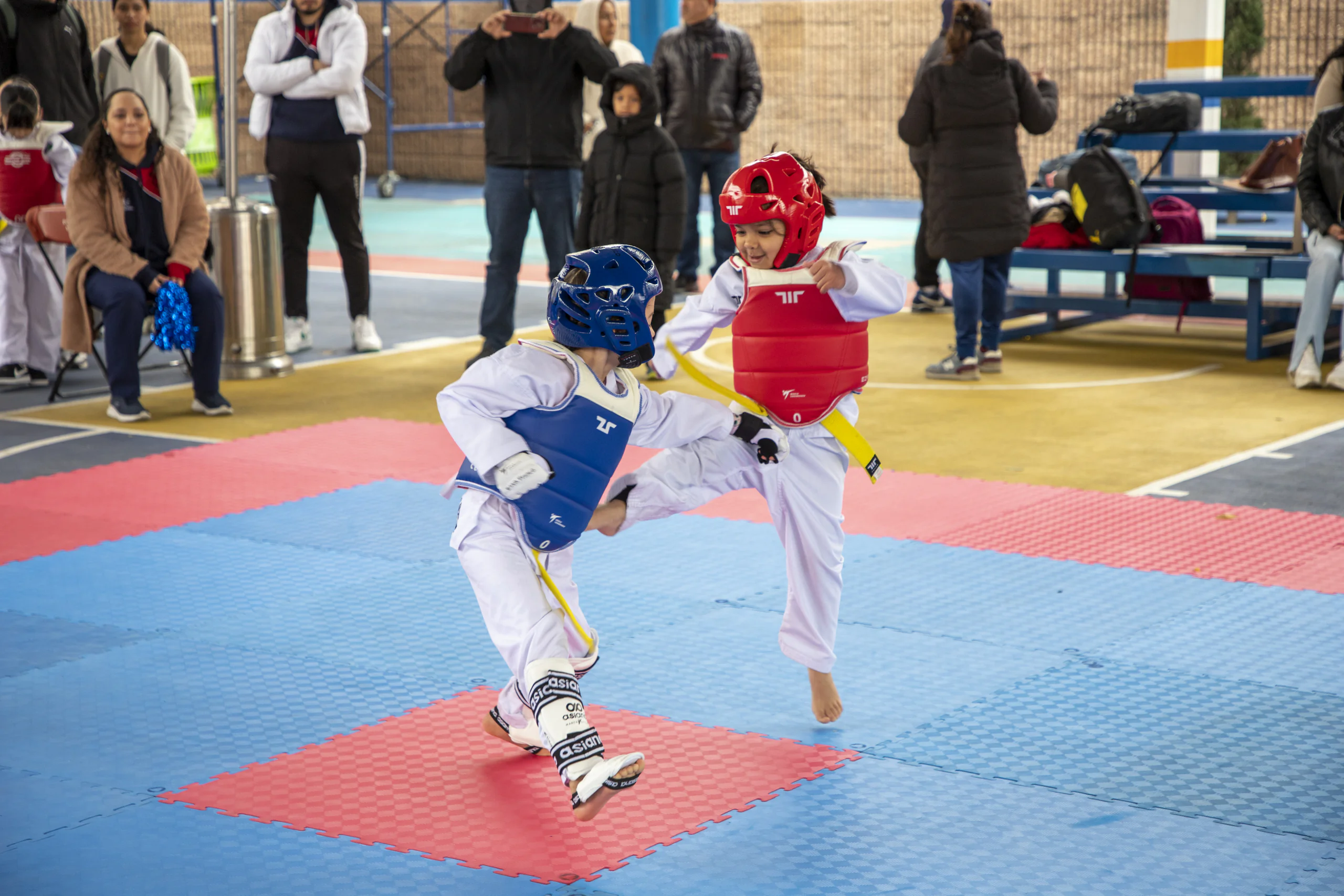 Combate de taekwondo infantil con protecciones azul y roja