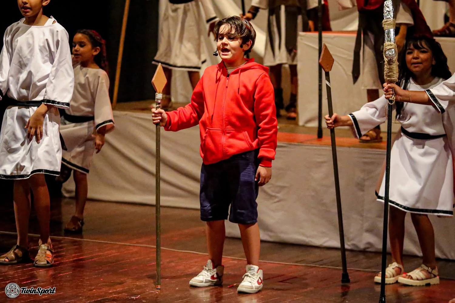 Montaje de teatro con vestuario blanco y lanzas