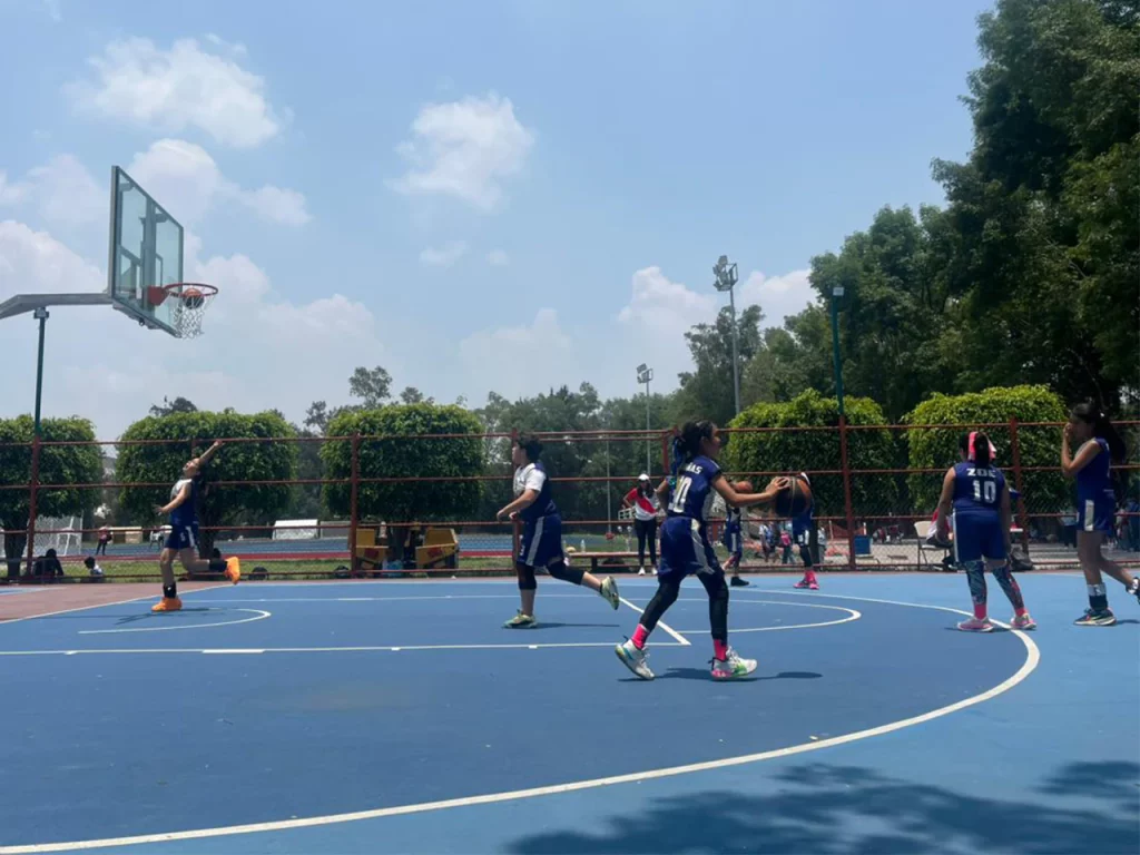 Alumnos de preparatoria jugando básquetbol en la cancha