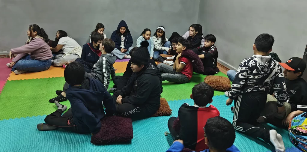 Niños sentados sobre tapetes de colores durante la clase de Interioridad