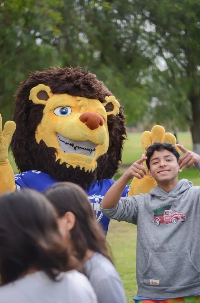 Un alumno posa junto a la botarga del león, mascota del colegio